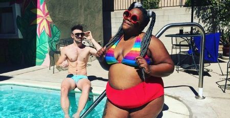 Nicole Byer poses in a bikini in front of a swimming pool.